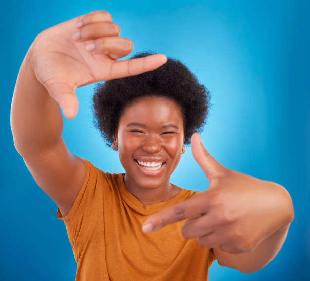 istock Finger framing, portrait and happy black woman on blue background, studio and backdrop. Face, female and hands frame perspective, pose and smile of happiness, photography or capture profile picture 1782041263