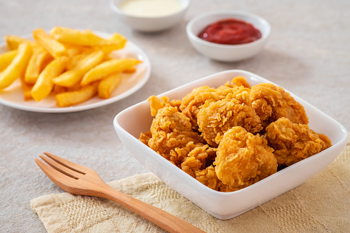 High resolution digital capture of a serving of crispy, golden, fried chicken strips, with ketchup, on a pure white background.