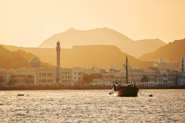 Old town of Muscat at golden sunset Harbor with traditional wooden boat Dhow and waterfront of old town in Muscat. Sultanate of Oman. corniche stock pictures, royalty-free photos & images