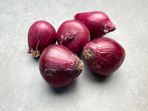Red onions on gray stone background with copy space