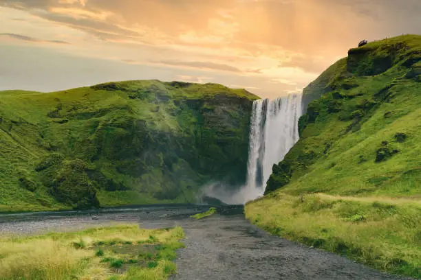 Famous Skogafoss waterfall on Skoga river. The majesty of nature is showcased in this stunning landscape with waterfall cascades down a lush, green cliffside. Exploration and adventure concept.