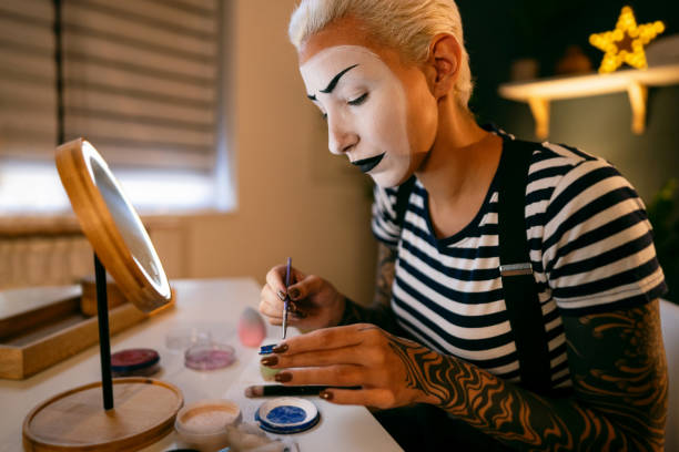 istock Young woman, a mime artist, applying face paint while getting ready for pantomime show. 1782074482