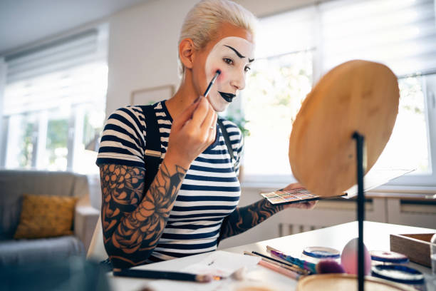 istock Young woman, a mime artist, applying face paint while getting ready for pantomime show. 1782075090