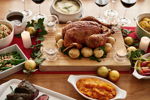 Chicken, vegetables and christmas food on a table for a family celebration dinner with decoration. Healthy meat, turkey and produce luxury holiday feast prepared for event in a dining room at home.