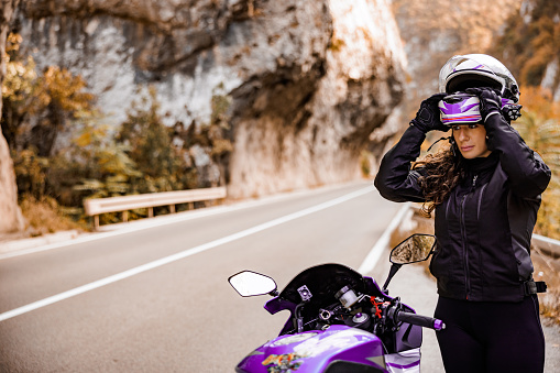 Female motorcycle rider puts crash helmet