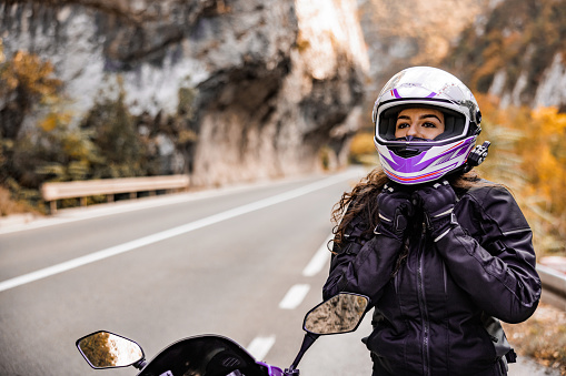 Beautiful female biker puts crash helmet
