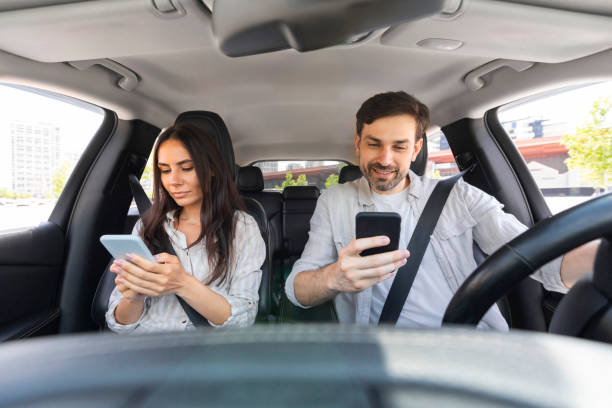 istock Millennial man and woman sitting inside car, using smartphones 1782125225