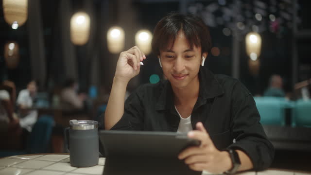 Asian man enjoy thinking work and using digital tablet at night.