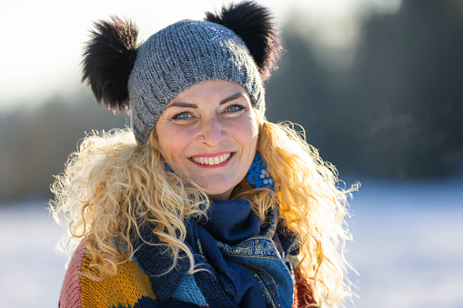 Beautiful happy woman at snowcapped meadow near forest in winter time.