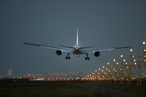Airplane landing at airport at night, dark sky