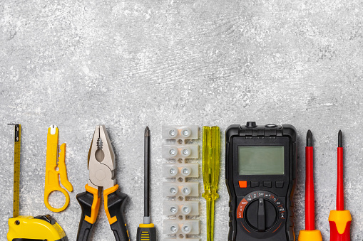 Electrician equipment on marble background with copy space.Top view.Electrician tool set.Multimeter, tester,screwdrivers,cutters,duct tape,lamps,tape measure and wires.Flet lay.