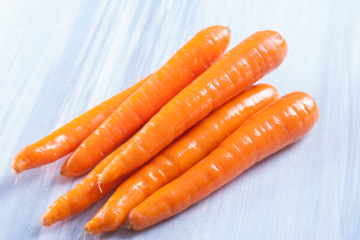 Close up photo of edible vegetables - a carrots on a solid light blue wooden table