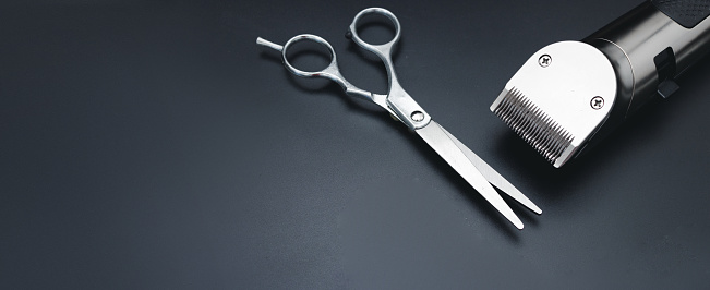 Hair clipper and Hairdresser scissors on black background. Mens hairdressing desktop with tools for shaving top view. Male haircut, fashion. Hairdresser salon equipment, premium hairdressing shears