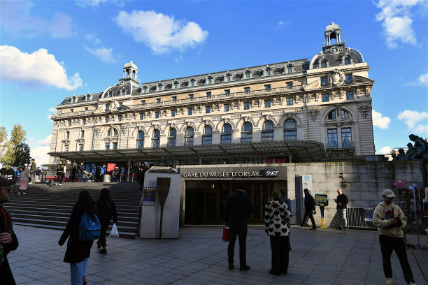 Paris, France - May 31, 2014: Tourists and Parisians stroll along the sidewalk and ramp past the The Musee d'Orsay in Paris  Located in a former railway station,   built between 1898 and 1900 on the left bank of the Seine, the museum houses major 19th- & 20th-century, European art collections