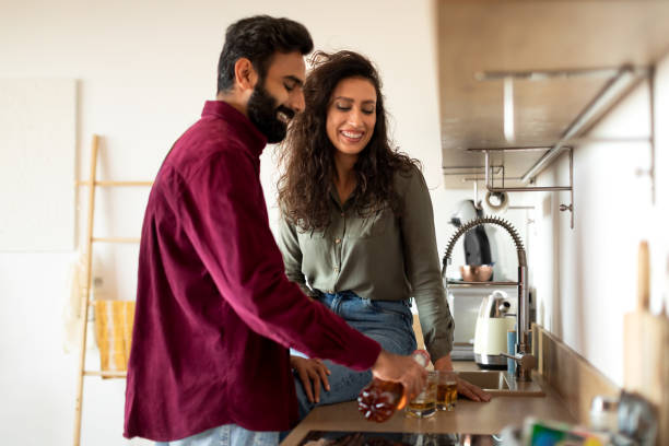 istock Happy arab couple drinking wine in kitchen interior, man pouring alcohol from bottle into glasses 1782208459