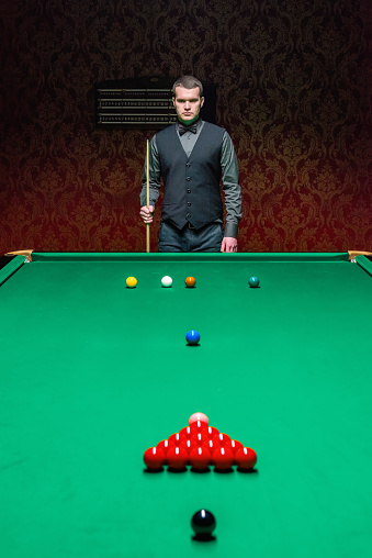 A proficient male snooker player demonstrates precision and focus on the snooker table.