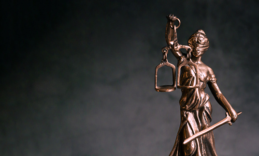 Themis statue Justice with scales on dark background. Legal and law concept