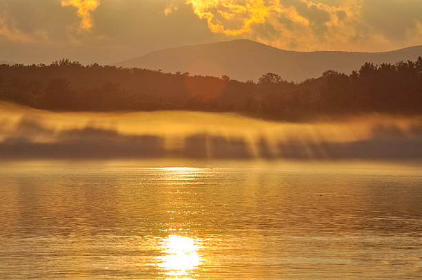 Pôr do sol sobre o rio na neblina - foto de acervo