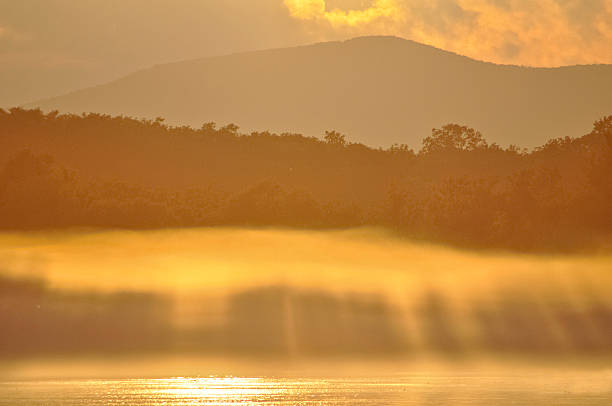Pôr do sol sobre o rio na neblina - foto de acervo