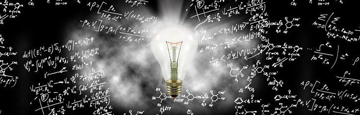 Image of a glowing light bulb on a background of handwritten mathematical expressions