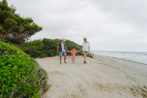 Photo of a senior couple and their grandson having a walk by the sea