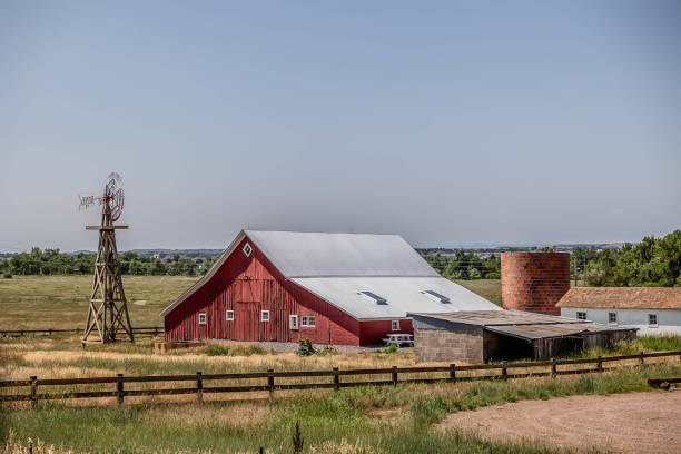 istock Red barn with windmill and a silo and a light blue sky 1782261347