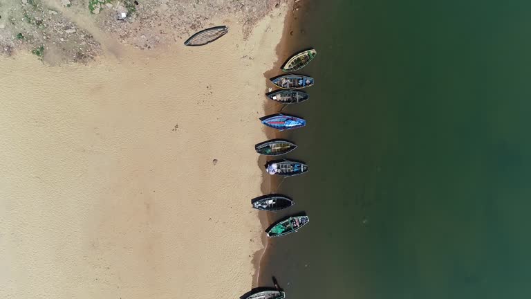 A stunning aerial view of boats docked by the beach, showcasing a vivid contrast between the golden sands and the glistening waters.