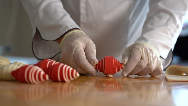 A French pastry chef rolls red croissant dough on the table