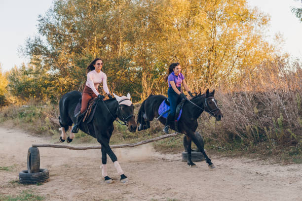 istock Two young women and their horses jump large jump while riding 1782300319