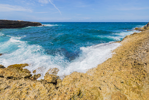 Beautiful view of natural landscape as incoming waves gracefully meet rugged coastline rocks along shores of Caribbean Sea in Aruba.
