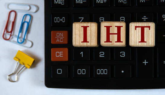 IHT (Inheritance tax) - abbreviation on wooden cubes on the background of a calculator and paper clips. Business concept