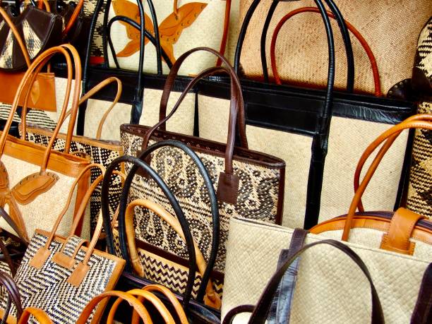 Horizontal closeup photo of a variety of handwoven natural fibre and leather baskets with handles arranged on a stall at the daily Craft Market in Ubud, Bali.