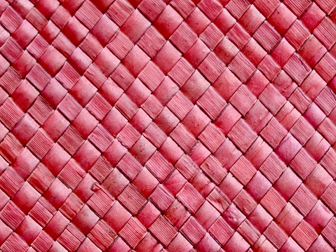 Horizontal closeup photo of part of a tightly woven pink plant fibre basket on a stall at the Ubud Craft Market, Ubud, Bali.