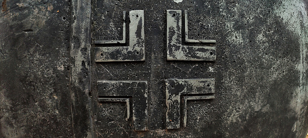 Emblem of the Wehmacht, the Nazi army of World War II. Metal bas-relief of a German cross. Balkenkreuz. Blackened old metal.