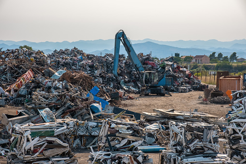 Clow crane picking up scrap metal at recycling center for metal, aluminum, brass, copper, stainless steel in junk yard. Recycling industry. Environment and zero waste concept.