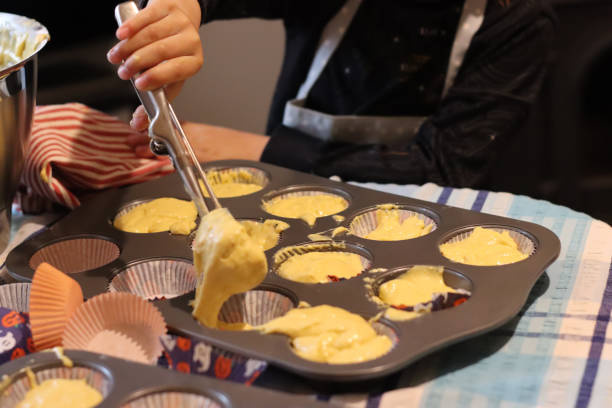 istock Kid hands making mess cup cake muffins for baking at home. Kid putting wet mixed cake in the baking tray. 1782401329