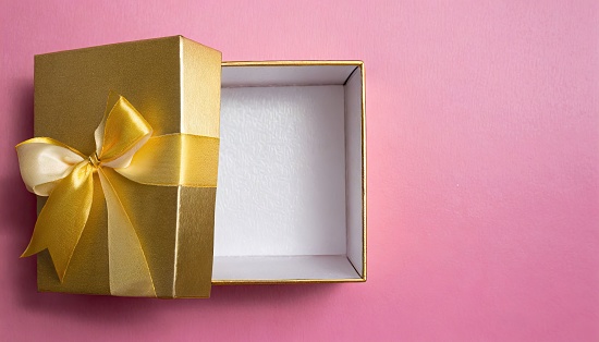 A vibrant pink background with an open gift box and a golden bow