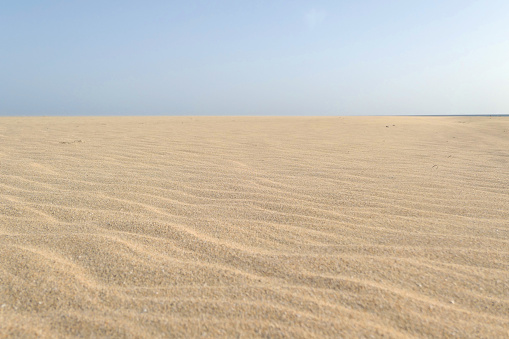 Jandia beach sand on Fuerteventura island. Playa de Jandia during calima. Spain, Europe. Selective focus on sand.