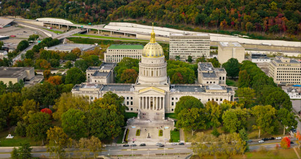 A high angle aerial still photo of the West Virginia State Capitol building on a cloudy day, with its roof visible in frame.