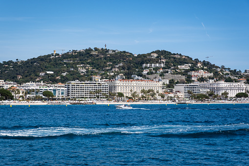 Cannes, France - May 4, 2023: People in a boat off the coast of Cannes with the Carlton Hotel in the background.