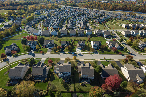 Aerial establishing shot of a residential district with numerous cookie-cutter houses, next to the Interstate 71, taken by a drone on a sunny Fall day in Grove City, Ohio.