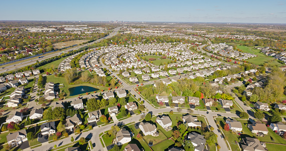 Aerial still image of a residential district with numerous cookie-cutter houses, next to the Interstate 71, taken by a drone on a sunny Fall day in Grove City, Ohio.