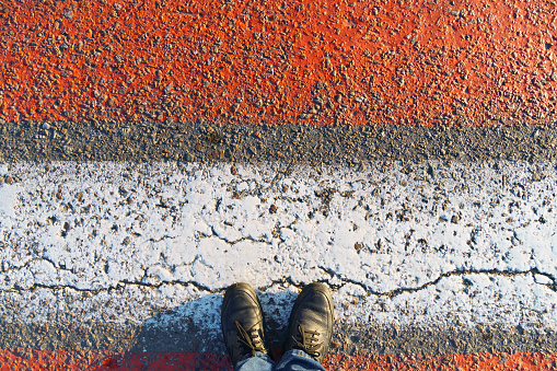 top view of the pedestrian crossing road markings and feet, red and white lines on the asphalt as a background