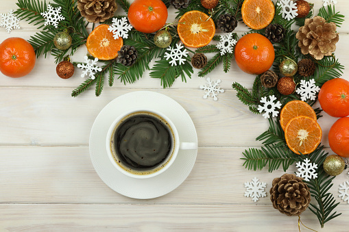 White wooden background with pattern of Christmas decorations, cup of coffee and copy space