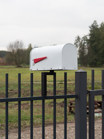 A pristine white mailbox stands as a welcoming sentinel at a countryside home. Framed by a sturdy metal fence in the foreground, it exudes an air of rural charm. Beyond the enclosure, a vast green field stretches into the distance, creating a picturesque scene. The simplicity of the mailbox juxtaposed against the lush surroundings captures the essence of a tranquil countryside dwelling. This snapshot, taken in November in Poland, evokes a sense of serenity and rural beauty.