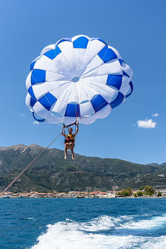 The majestic unfurling of the parachute complements the young woman's ascent, marking her departure from the sea and entrance into the sky