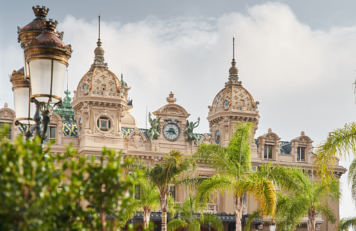 Monaco, Monte-Carlo, 21 October 2022: Facade of Casino Monte-Carlo at sunny day, wealth life, famous landmark, pine trees, blue sky. High quality photo