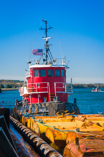 An industrial red tugboat pushes yellow tanks east on the Cape Cod canal on November morning,