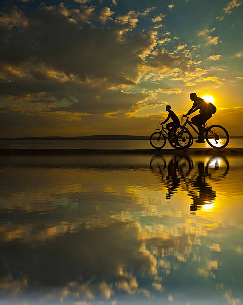 istock two mountain biker silhouette  sunrise with reflection in water 178271705