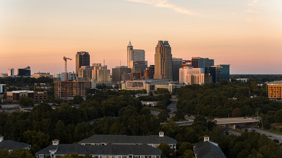 Urban transformation in North Carolina: sunset paints Downtown Raleigh, NC skyline. Gantry cranes and building activity in the Business District.